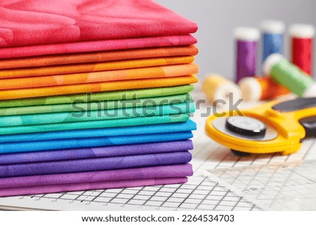 Stack of bright multicolored fabrics, accessories for sewing and quilting