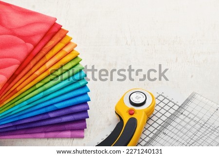 Stack of bright multicolored fabrics, accessories for quilting. Space for text.