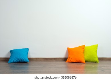 Stack Of Bright Pillows On Wooden Floor