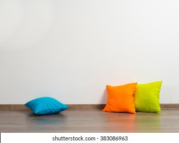 Stack Of Bright Pillows On Wooden Floor