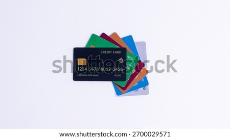 Stack of brightly colored credit cards, with the black card prominently displayed, fanned out on a white background, symbolizing diverse financial choices, payment methods, or banking services.
