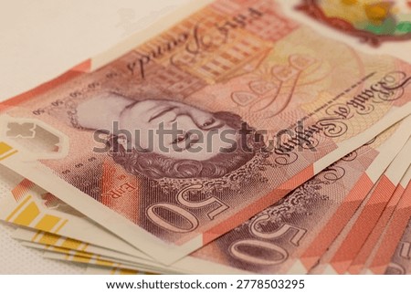 Stack of British fifty-pound banknotes featuring Queen Elizabeth II.