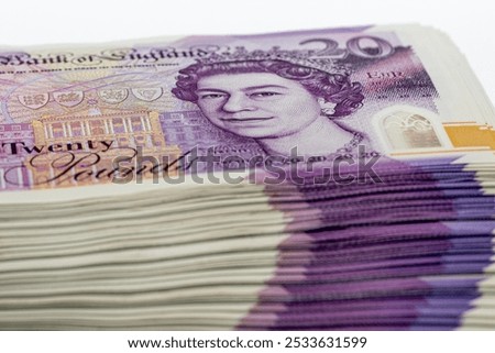 A stack of British twenty pound banknotes with Queen Elizabeth II on the front, the face value visible on the topmost bill.