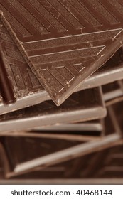 Stack of broken dark chocolate bar close-up.