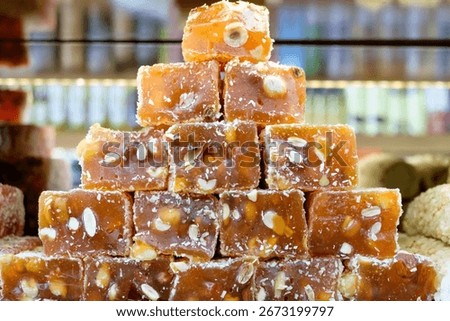 Stack of brown candies with nuts on top. The candies are piled on top of each other