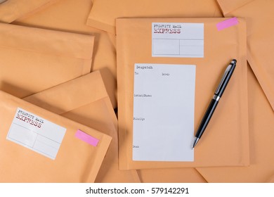 Stack of bubble wrap padded mailing envelopes and pen on white background color over wooden table. Envelope packaging shockproof stack concept.
