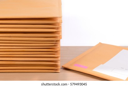 Stack of bubble wrap padded mailing envelopes on white background color over wooden table. Envelope packaging shockproof stack concept.