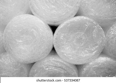 A stack of bubble wrap rolls. Close up of packing material or rolled-up bubble plastic. Can be used to protect and move fragile objects. 
Background with a repeated pattern of round shapes. 