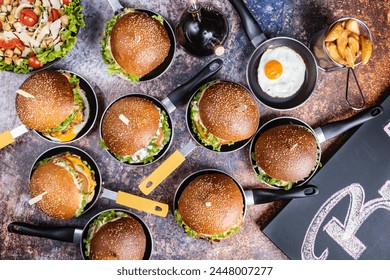 A stack of burgers in tiny pans, photographed from above: A tantalizing view of delicious burgers, each in its own small skillet, showcasing various toppings and flavors. - Powered by Shutterstock