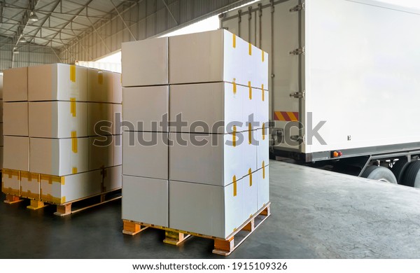 Stack\
of cardboard boxes on pallet rack load into shipping container.\
Supply Chain cargo shipment boxes. trailer parked at loading dock\
warehouse. industry freight truck\
transportation.