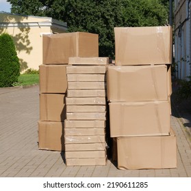 Stack of cardboard boxes of various sizes in yard of house. Concept of moving.  Background for your projects and creative work. Focus on foreground.
