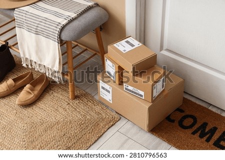 Stack of cardboard delivery boxes on a welcome mat at a residential front door, online shopping and shipping concept, Multiple packages with shipping labels are ready for pickup or recently