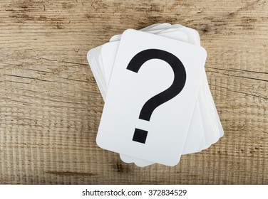 Stack of cards with a question mark on the old wooden background