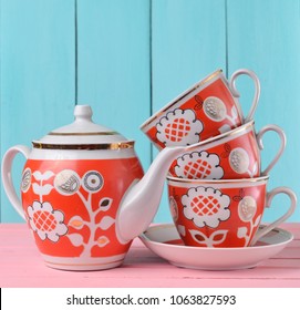 A stack of ceramic retro cups with red patternsand teapot on a pink wooden table against a blue wooden wall background, pastel color trend
 - Powered by Shutterstock