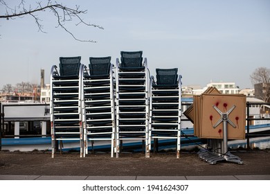 Stack of chairs and tables put together on a street. A pile of street cafe furniture and equipment. Start of tourism season. Stock photography.