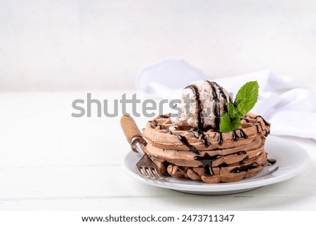 Stack of chocolate belgian waffles with ice cream and chocolate topping. Breakfast waffles with gelato, chocolate sauce drizzles and mint