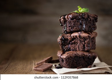 A stack of chocolate brownies on wooden background with mint leaf on top, homemade bakery and dessert