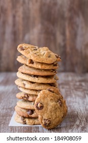 A Stack Of Chocolate Chip Cookies With One Leaning