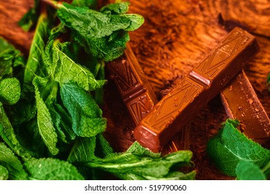 stack of chocolate pieces with a  leaf of mint on wooden background