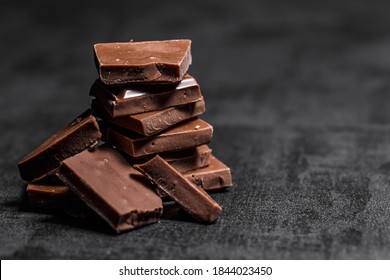 Stack of chocolate slices with mint leaf on a wooden table.Assortment of fine chocolates in white, dark, and milk chocolate. Sweet food photo concept.