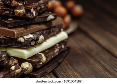 Stack of chocolate slices with mint leaf on a wooden table.Assortment of fine chocolates in white, dark, and milk chocolate. Sweet food photo concept.