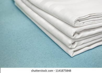 Stack Of Clean Bed Sheets On Color Background, Closeup