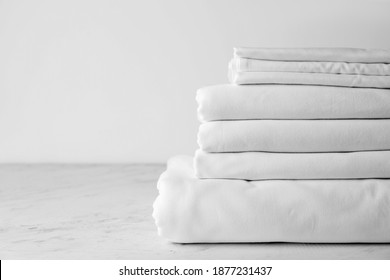 Stack of clean bed sheets on table - Shutterstock ID 1877231437