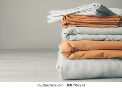 Stack of clean bed sheets on table - Shutterstock ID 1887369271