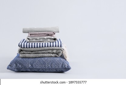 Stack of clean bed sheets and pillow on white background