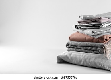 Stack of clean bed sheets and pillow on white background. Space for text