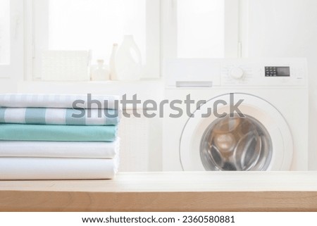 Stack of clean bedsheets on blurred washing machine interior background