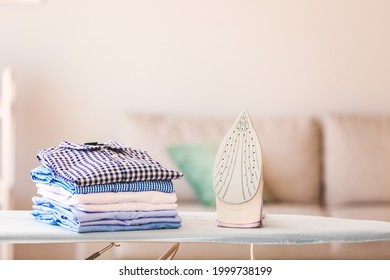 Stack of clean clothes on ironing board in room