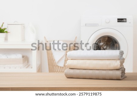 Stack of clean folded textile duvet covers on blurred laundry room background