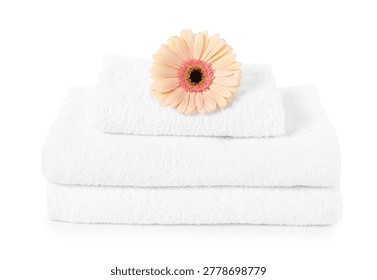 Stack of clean folded towels and gerbera flower isolated on white