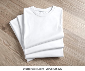 Stack of clean, folded white shirts on a light wood surface, overhead shot