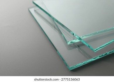Stack of clean glass sheets on grey background, closeup. Space for text
