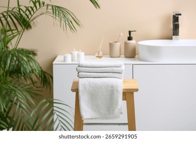 Stack of clean soft towels on wooden table in interior of modern bathroom