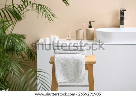Stack of clean soft towels on wooden table in interior of modern bathroom