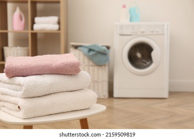 Stack of clean terry towels on white table in laundry room. Space for text