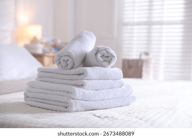 Stack of clean towels on bed linens at home, closeup