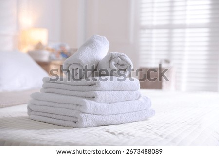 Stack of clean towels on bed linens at home, closeup