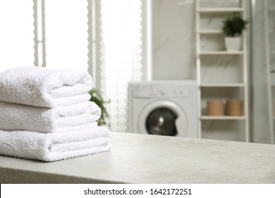 Stack Of Clean Towels On Table In Laundry Room. Space For Text