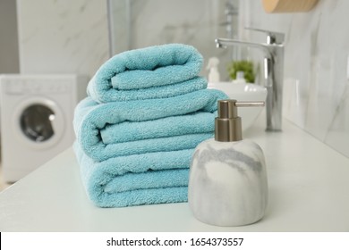 Stack of clean towels and soap dispenser on countertop in bathroom - Shutterstock ID 1654373557