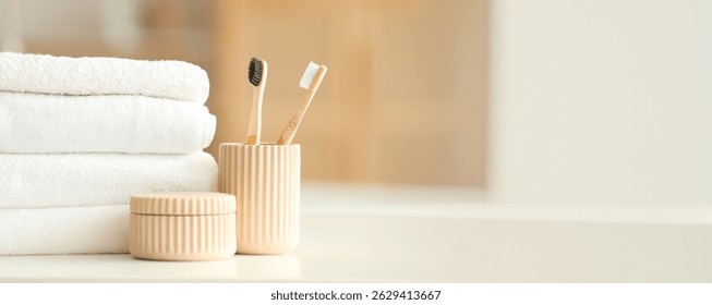 Stack of clean towels and toothbrushes on table in bathroom. Banner for design