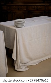 Stack of Clean White Plates on Linen Covered Banquet Table Preparing for Wedding Reception Catering Service