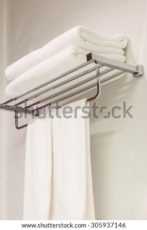 Stack of clean white towels on stainless steel rack in restroom for shower background