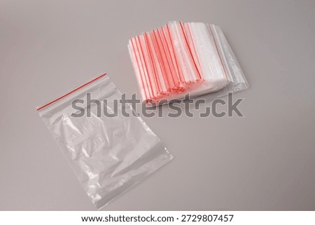 stack of clear plastic zipper bags on grey background. packaging material for small business retail storage organization jewelry parts shipping hardware food safety reusable poly zip lock pouches