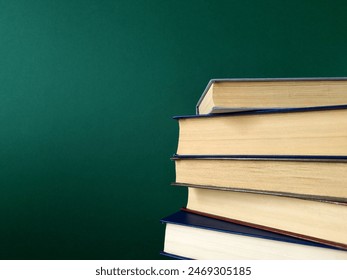 Stack of closed hardback books on green background. Close up