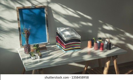 Stack Of Clothes On Table, Fresh Folded Cotton Clothing, Colorful Thread On Table, Silk Screen Frame