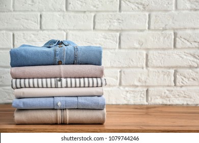 Stack Of Clothes On Table Near Brick Wall